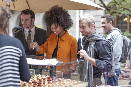 Woman choosing pastries at food stall at city market